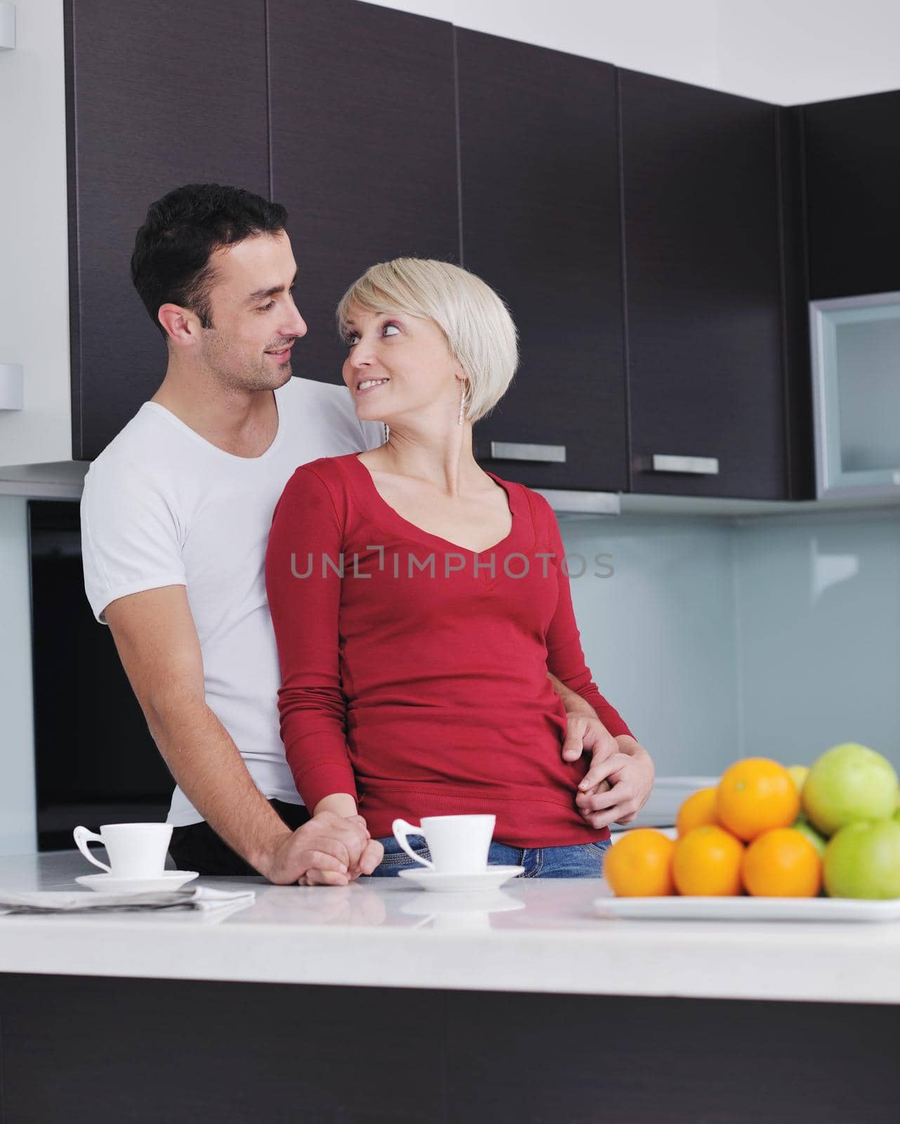 happy young couple have fun in  modern kitchen indoor  while preparing fresh fruits and vegetables food salad