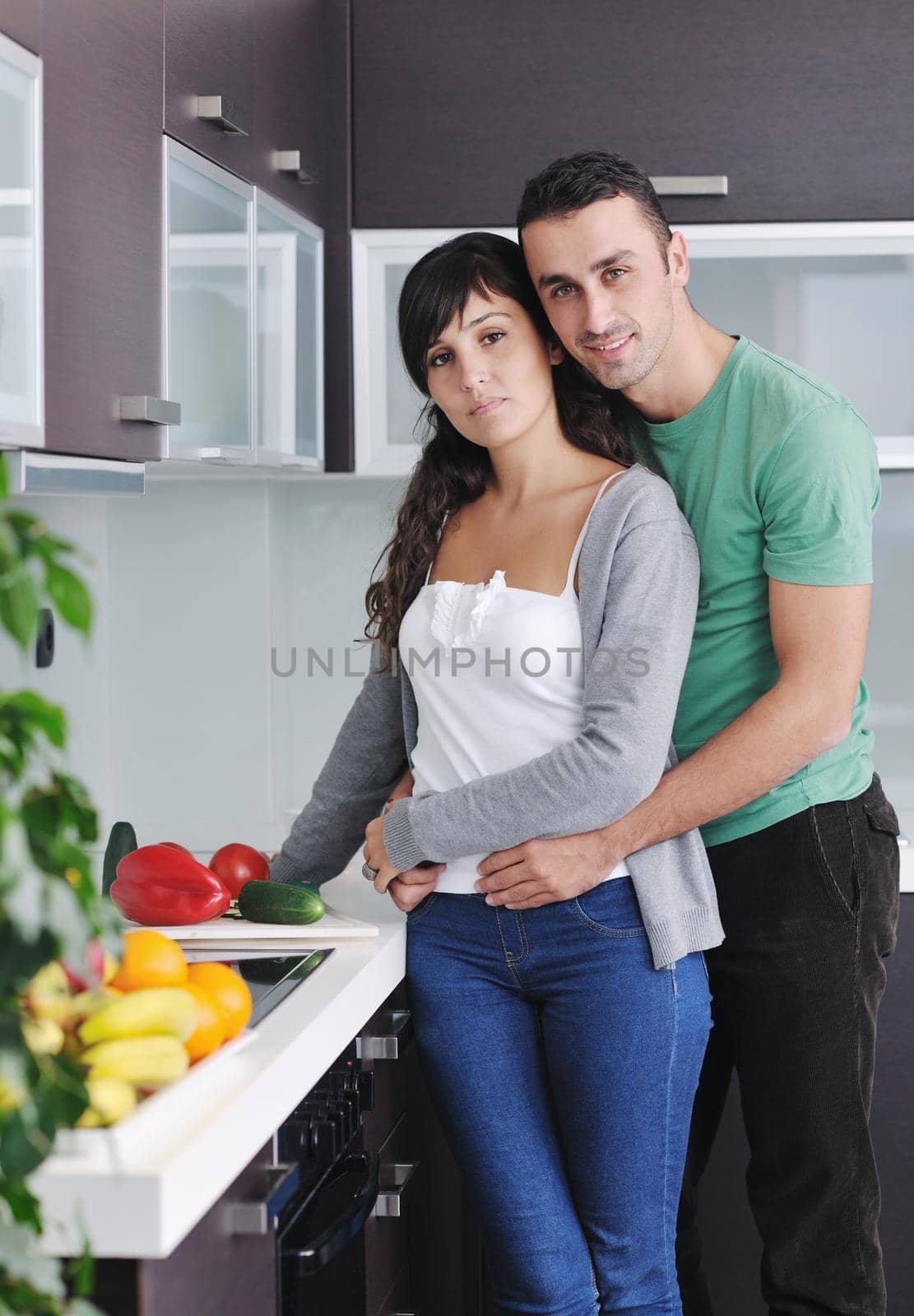 happy young couple have fun in  modern kitchen indoor  while preparing fresh fruits and vegetables food salad