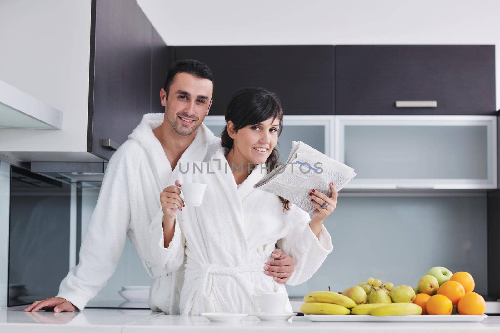 Happy couple reading the newspaper in the kitchen at breakfast by dotshock