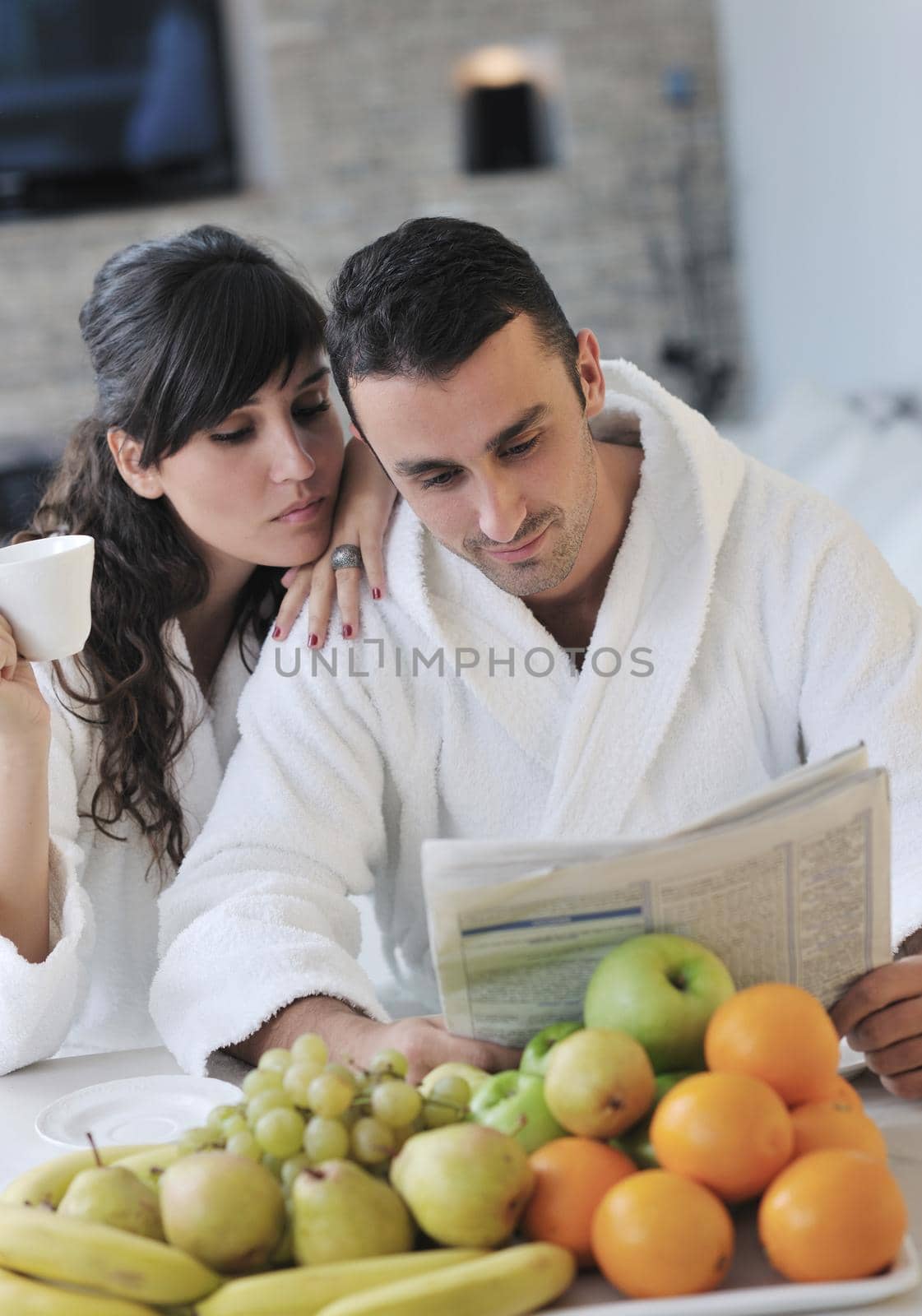Happy couple reading the newspaper in the kitchen at breakfast by dotshock