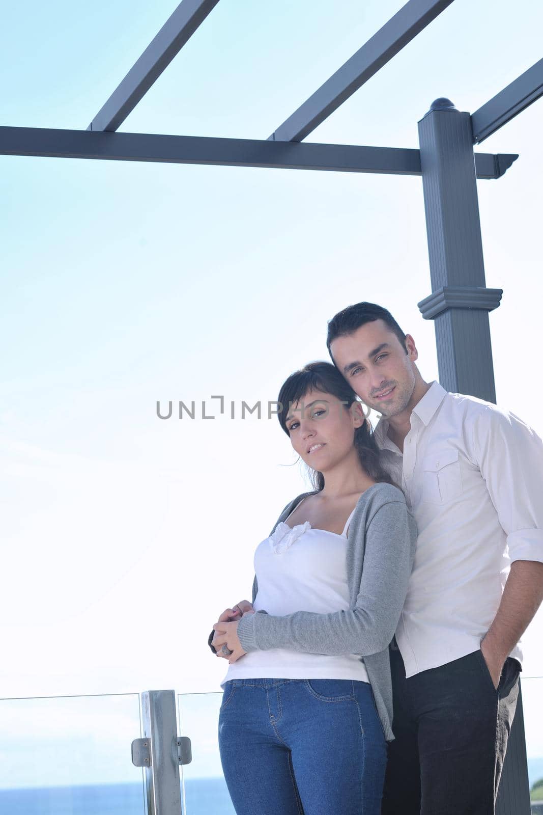 happy young couple relax on balcony outdoor with ocean and blue sky in background