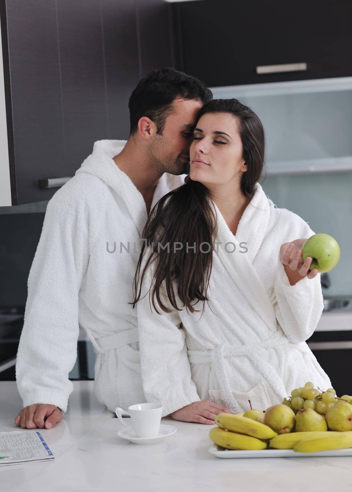 happy young couple have fun in  modern kitchen indoor  while preparing fresh fruits and vegetables food salad