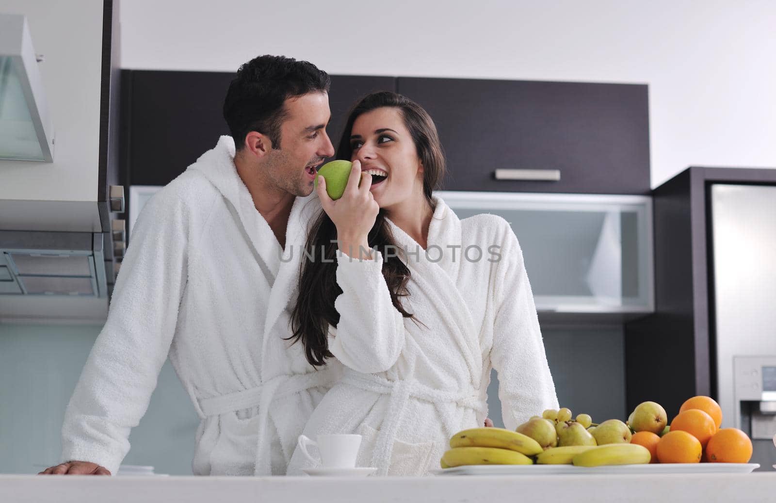 happy young couple have fun in  modern kitchen indoor  while preparing fresh fruits and vegetables food salad