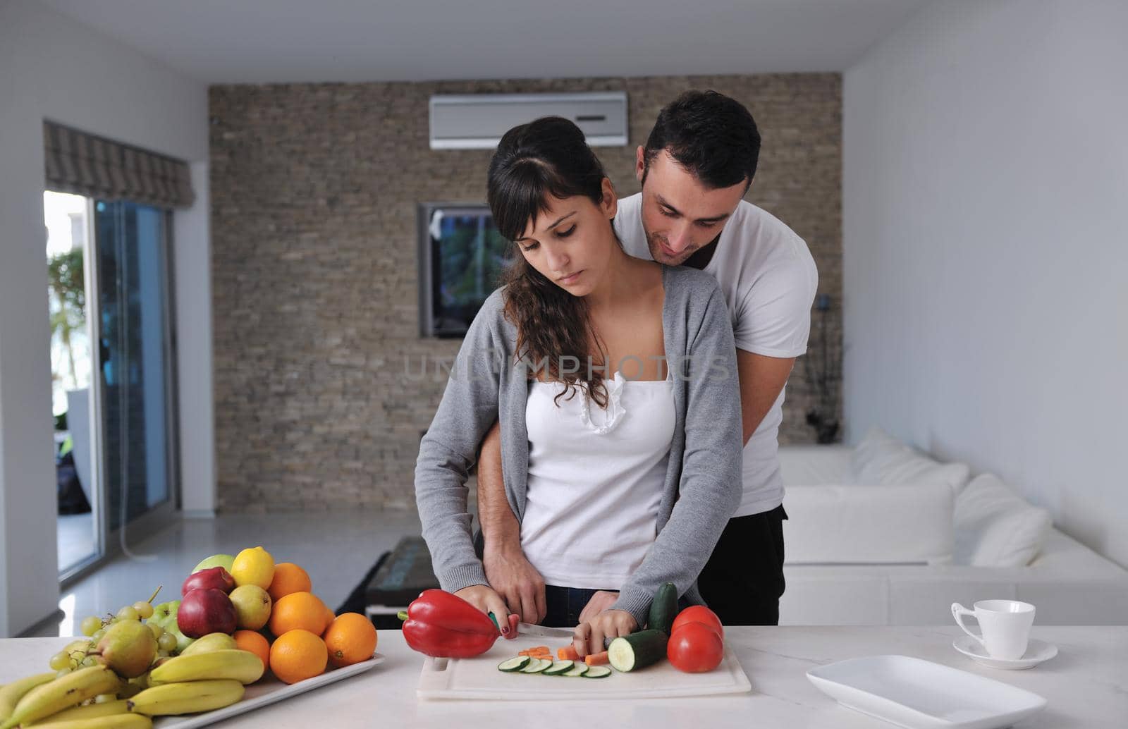 happy young couple have fun in  modern kitchen indoor  while preparing fresh fruits and vegetables food salad