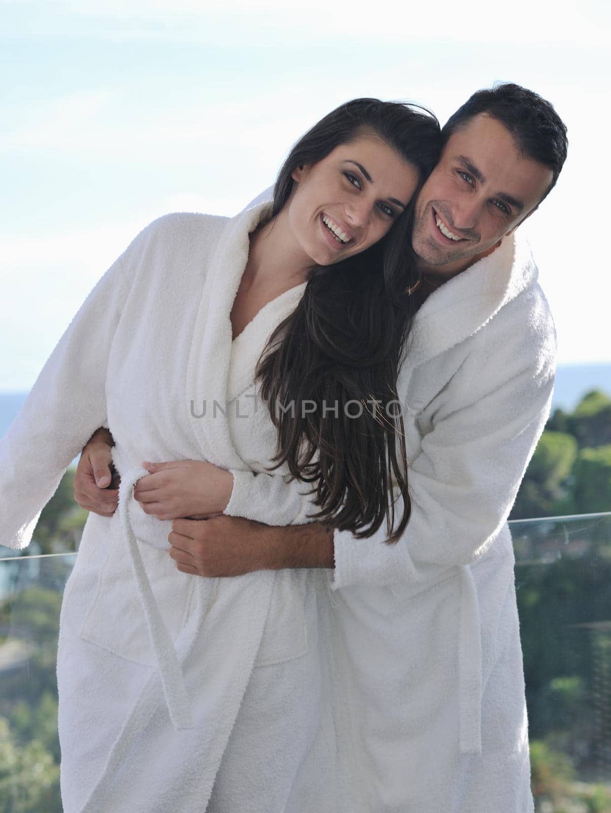 happy young couple relax on balcony outdoor with ocean and blue sky in background