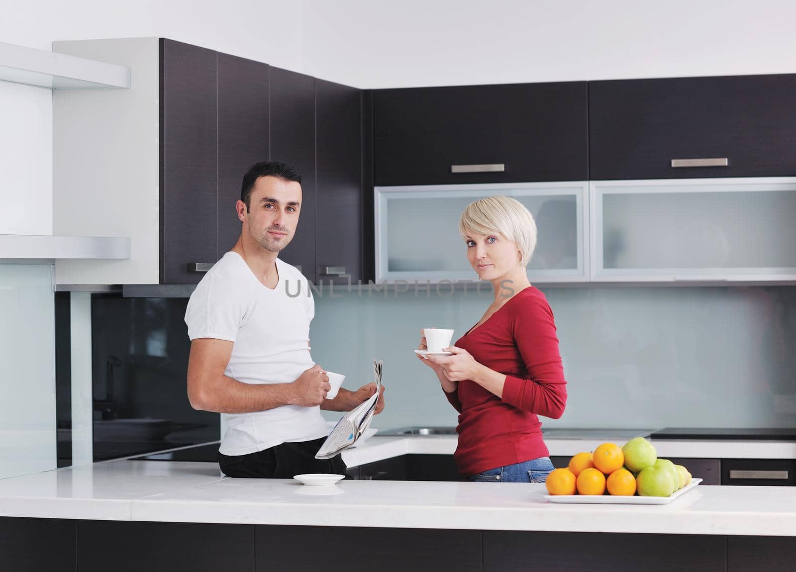 Happy couple reading the newspaper in the kitchen at breakfast by dotshock