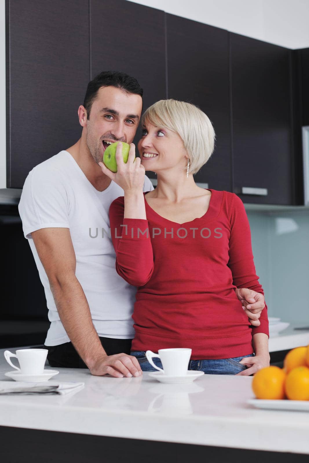 happy young couple have fun in  modern kitchen indoor  while preparing fresh fruits and vegetables food salad