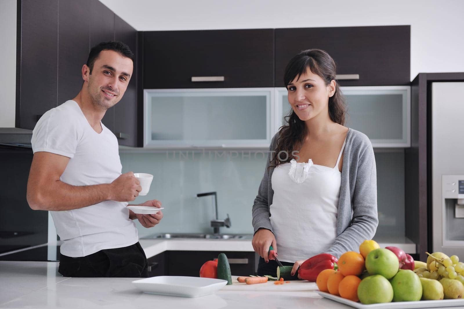 happy young couple have fun in  modern kitchen indoor  while preparing fresh fruits and vegetables food salad