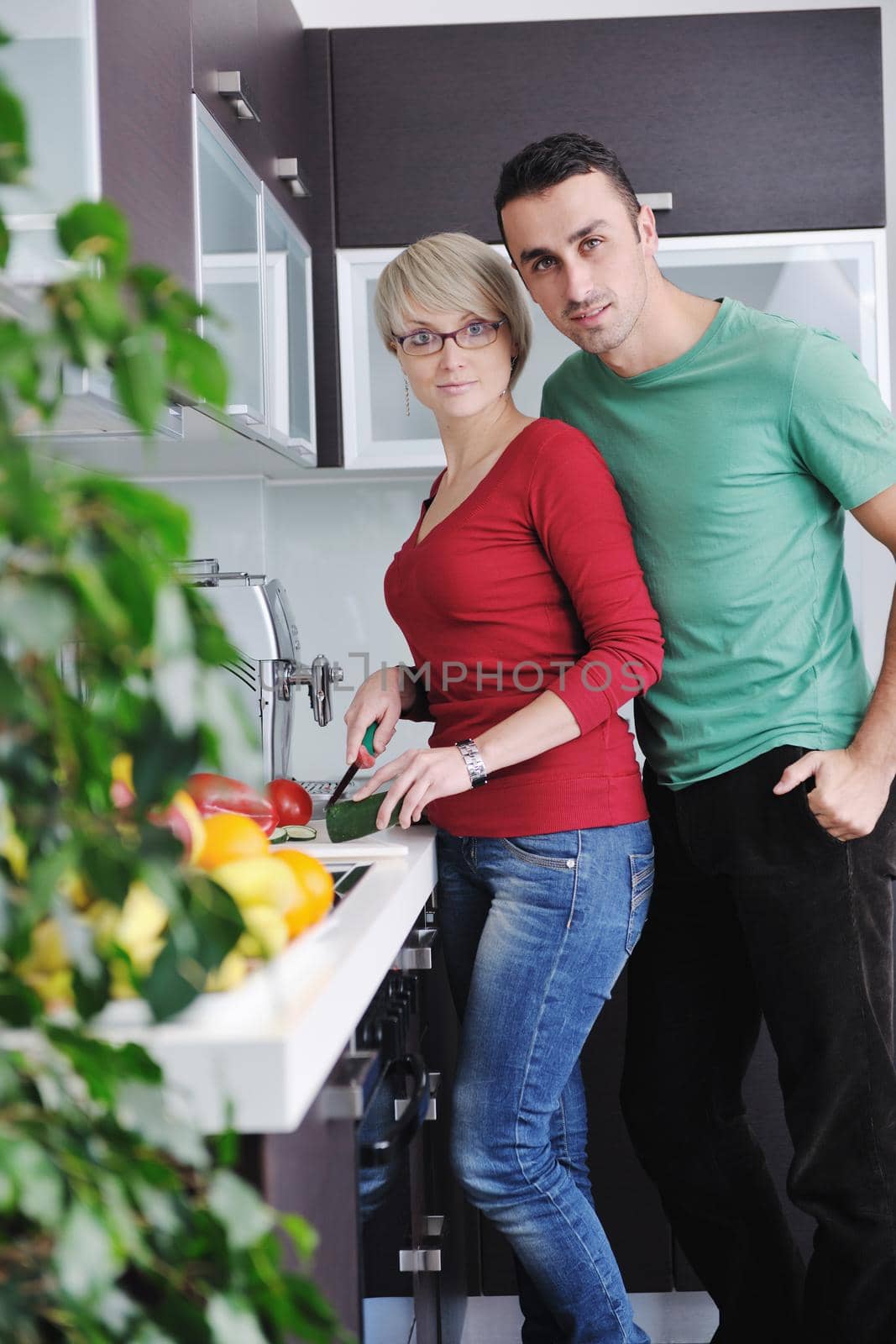 happy young couple have fun in  modern kitchen indoor  while preparing fresh fruits and vegetables food salad