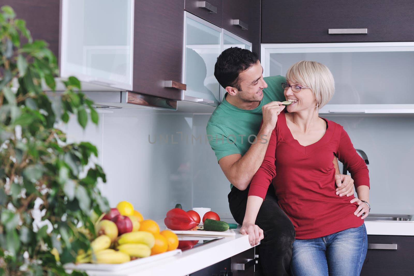 happy young couple have fun in  modern kitchen indoor  while preparing fresh fruits and vegetables food salad