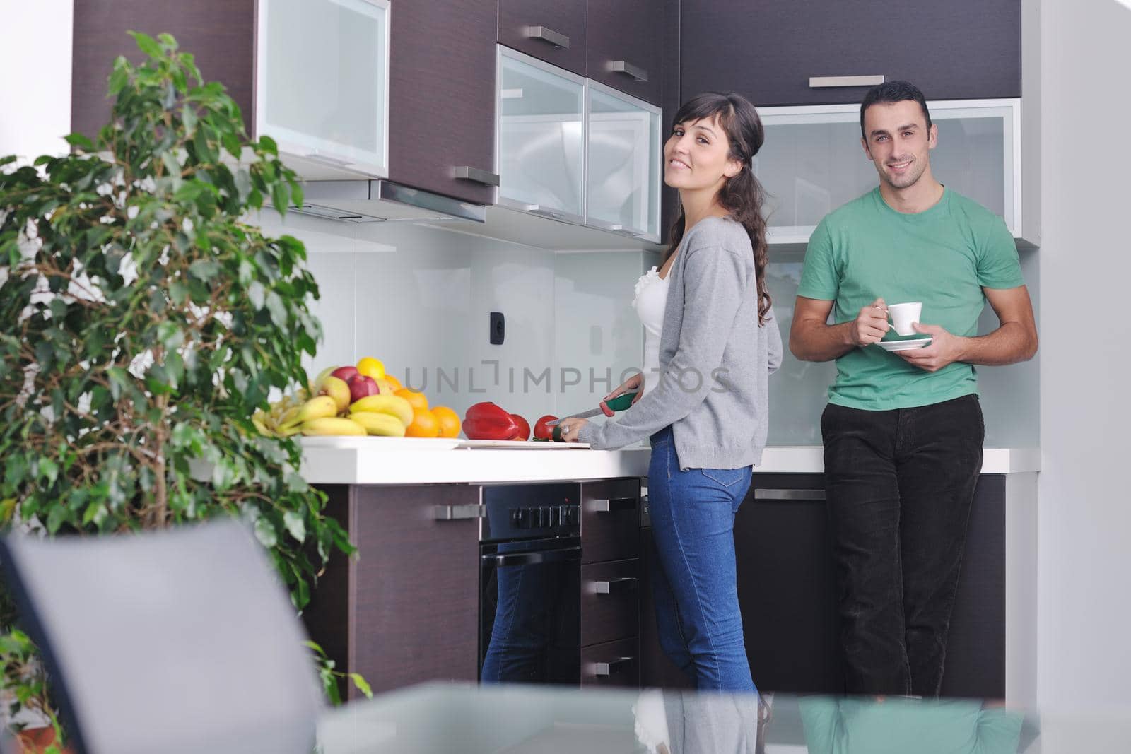 happy young couple have fun in  modern kitchen indoor  while preparing fresh fruits and vegetables food salad