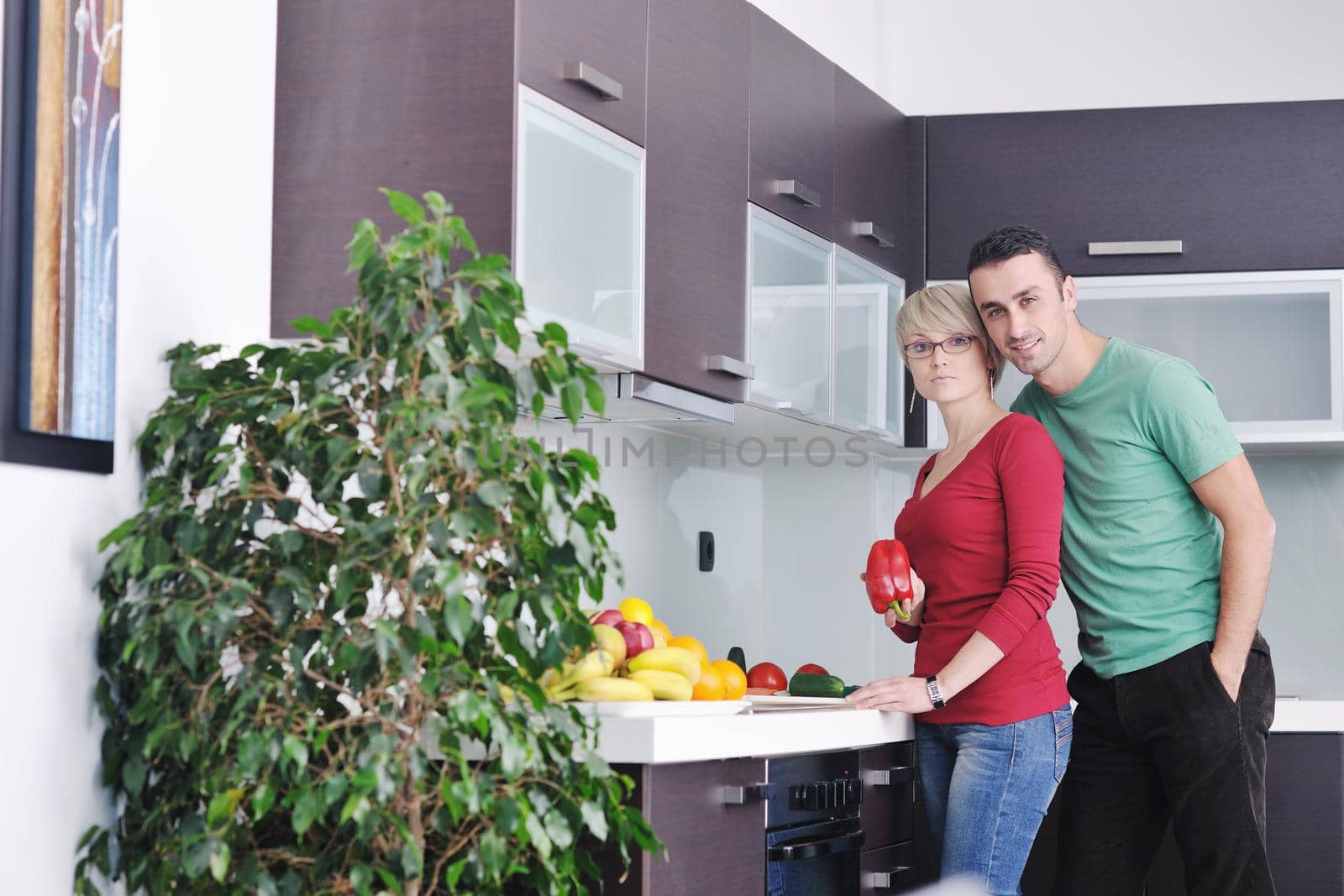 happy young couple have fun in  modern kitchen indoor  while preparing fresh fruits and vegetables food salad