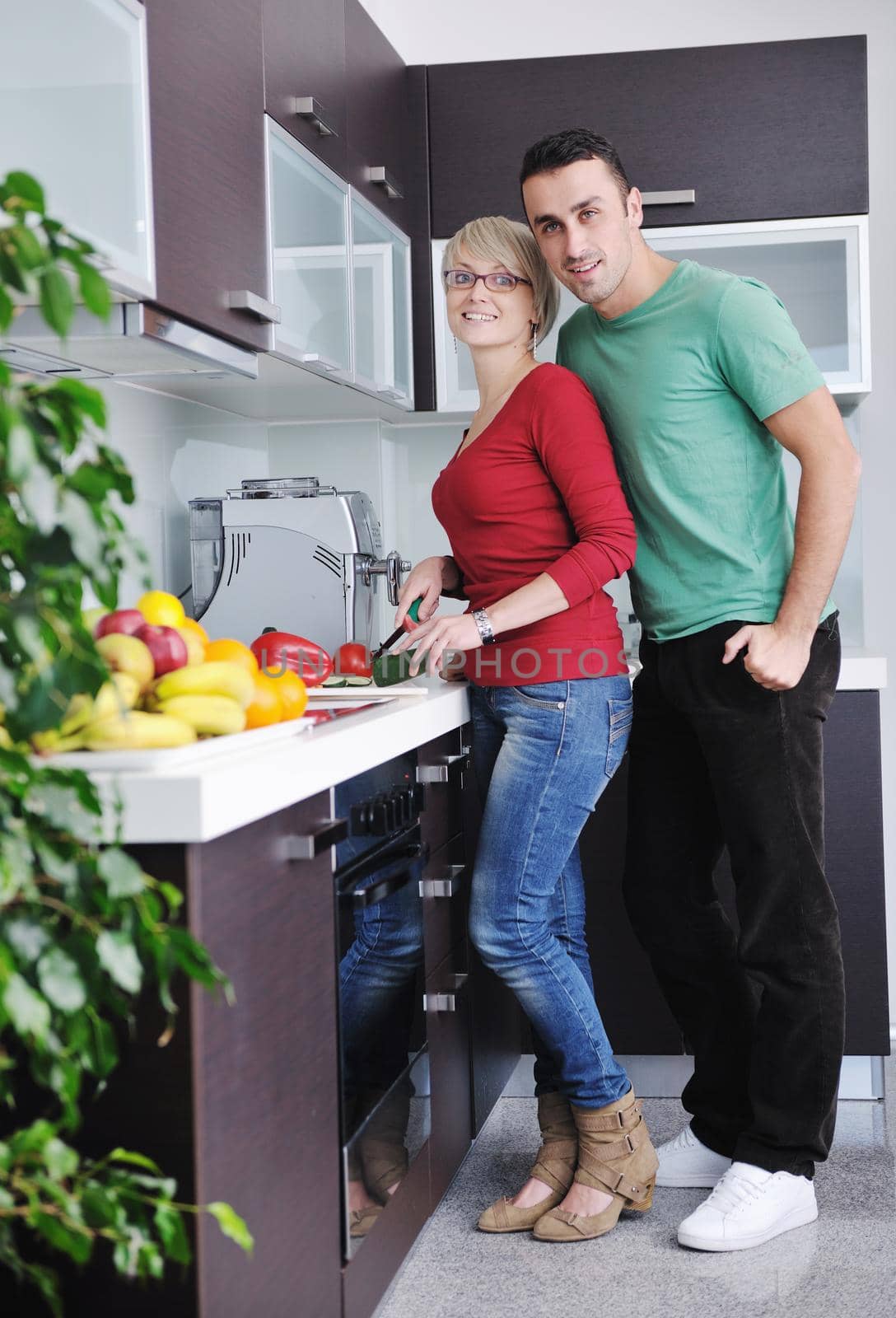 happy young couple have fun in  modern kitchen indoor  while preparing fresh fruits and vegetables food salad