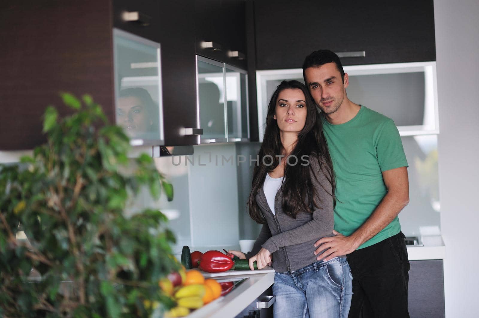 happy young couple have fun in  modern kitchen indoor  while preparing fresh fruits and vegetables food salad