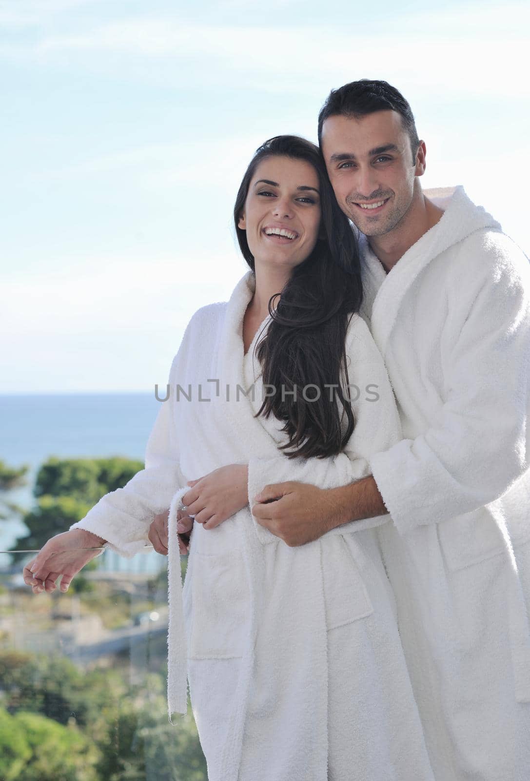 happy young couple relax on balcony outdoor with ocean and blue sky in background