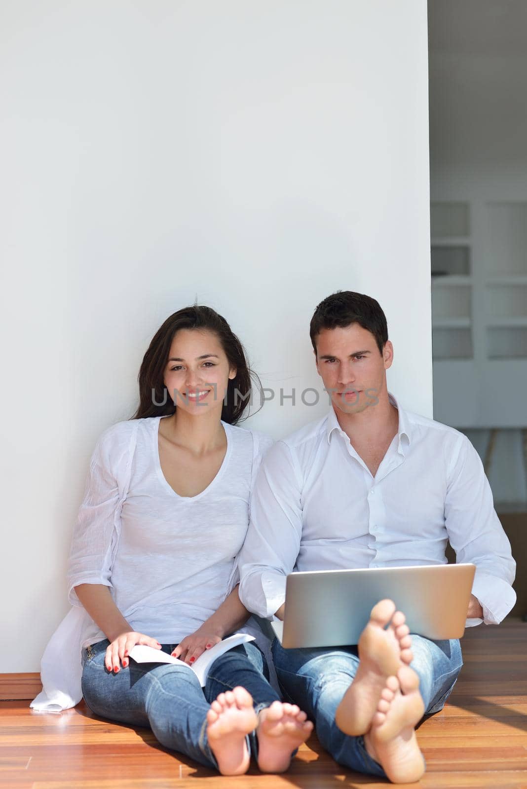 happy young relaxed  couple working on laptop computer at modern home indoor