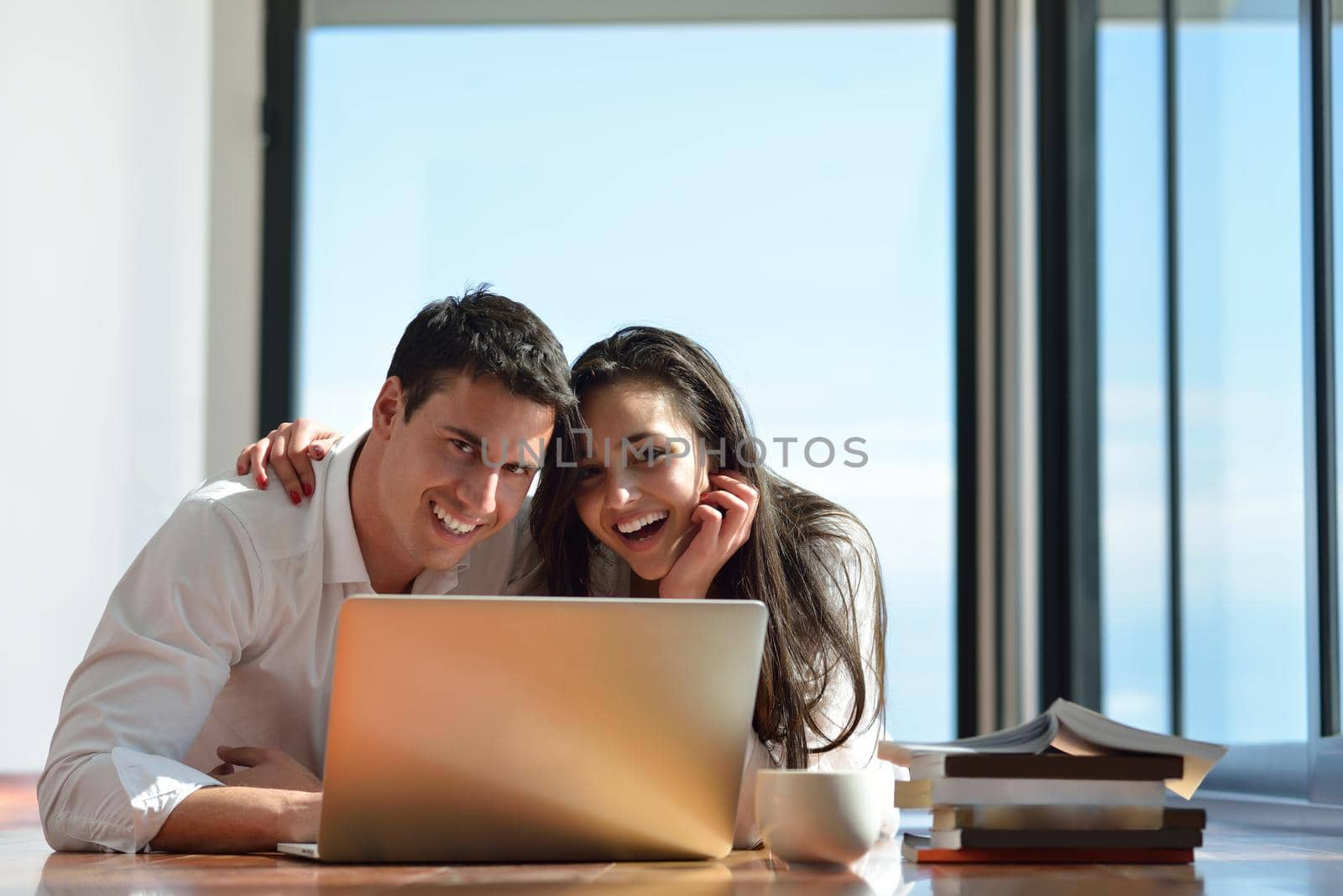 happy young relaxed  couple working on laptop computer at modern home indoor