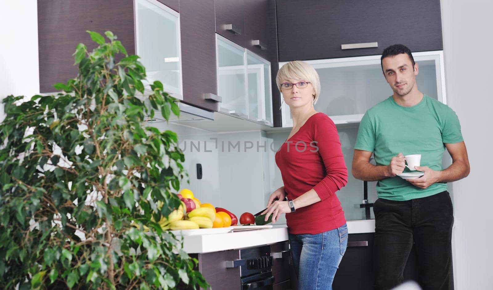 happy young couple have fun in  modern kitchen indoor  while preparing fresh fruits and vegetables food salad