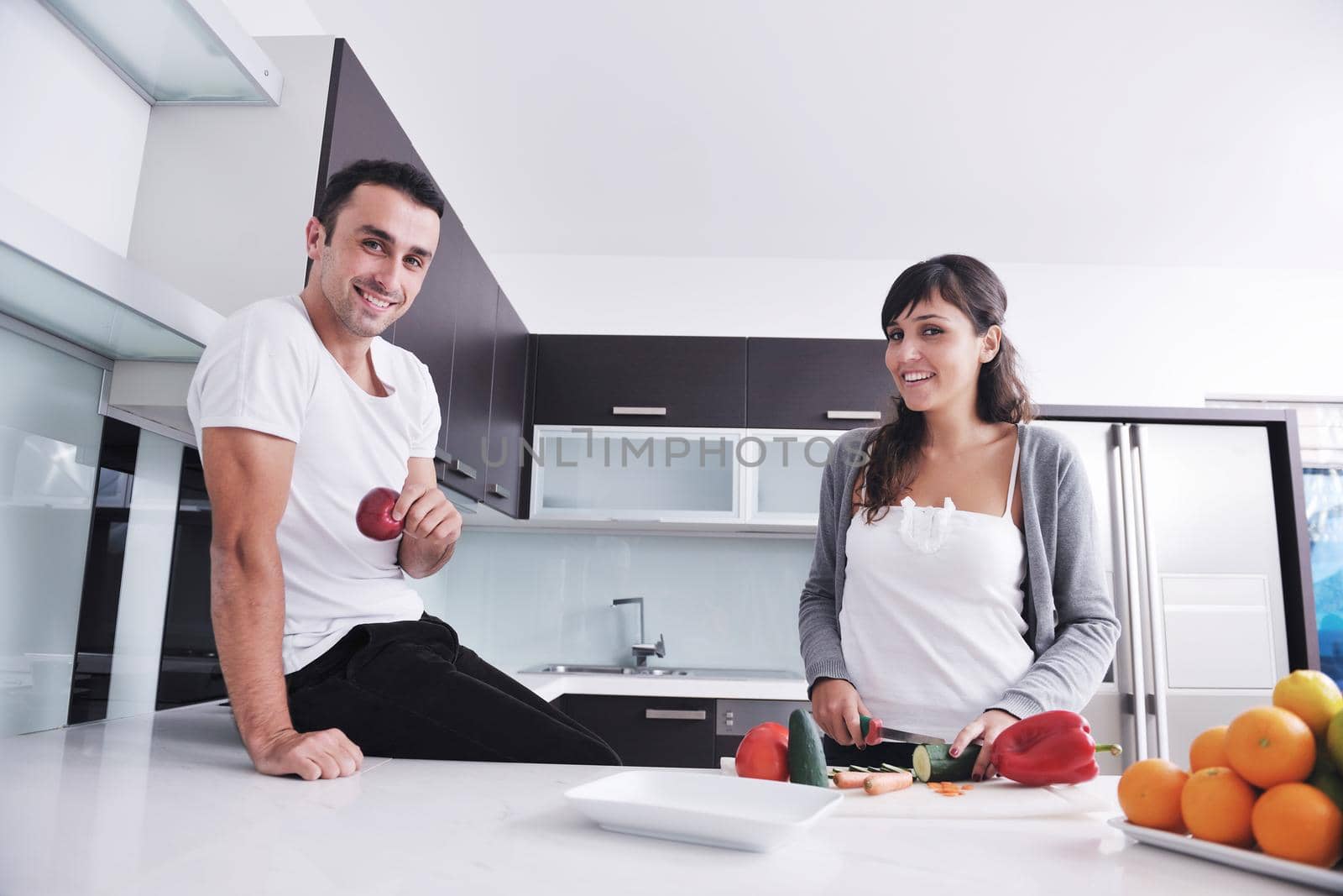 happy young couple have fun in  modern kitchen indoor  while preparing fresh fruits and vegetables food salad