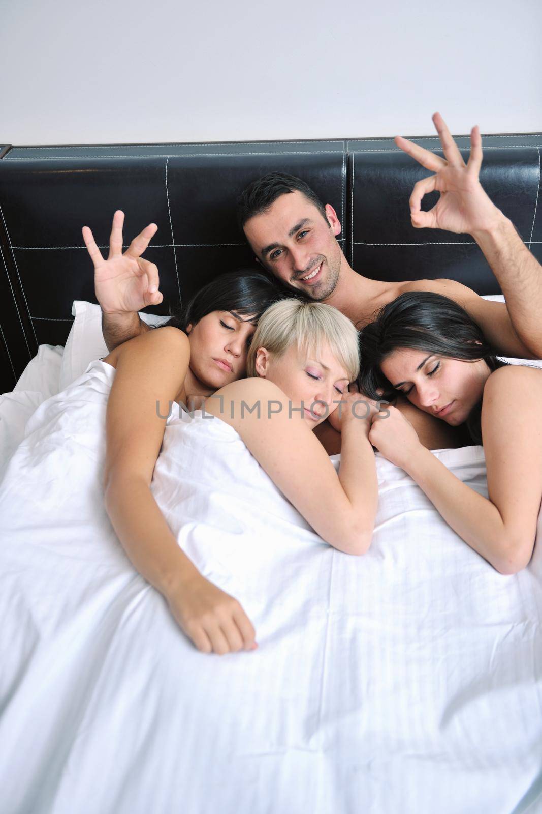 Young handsome man lying in bed with three girls by dotshock