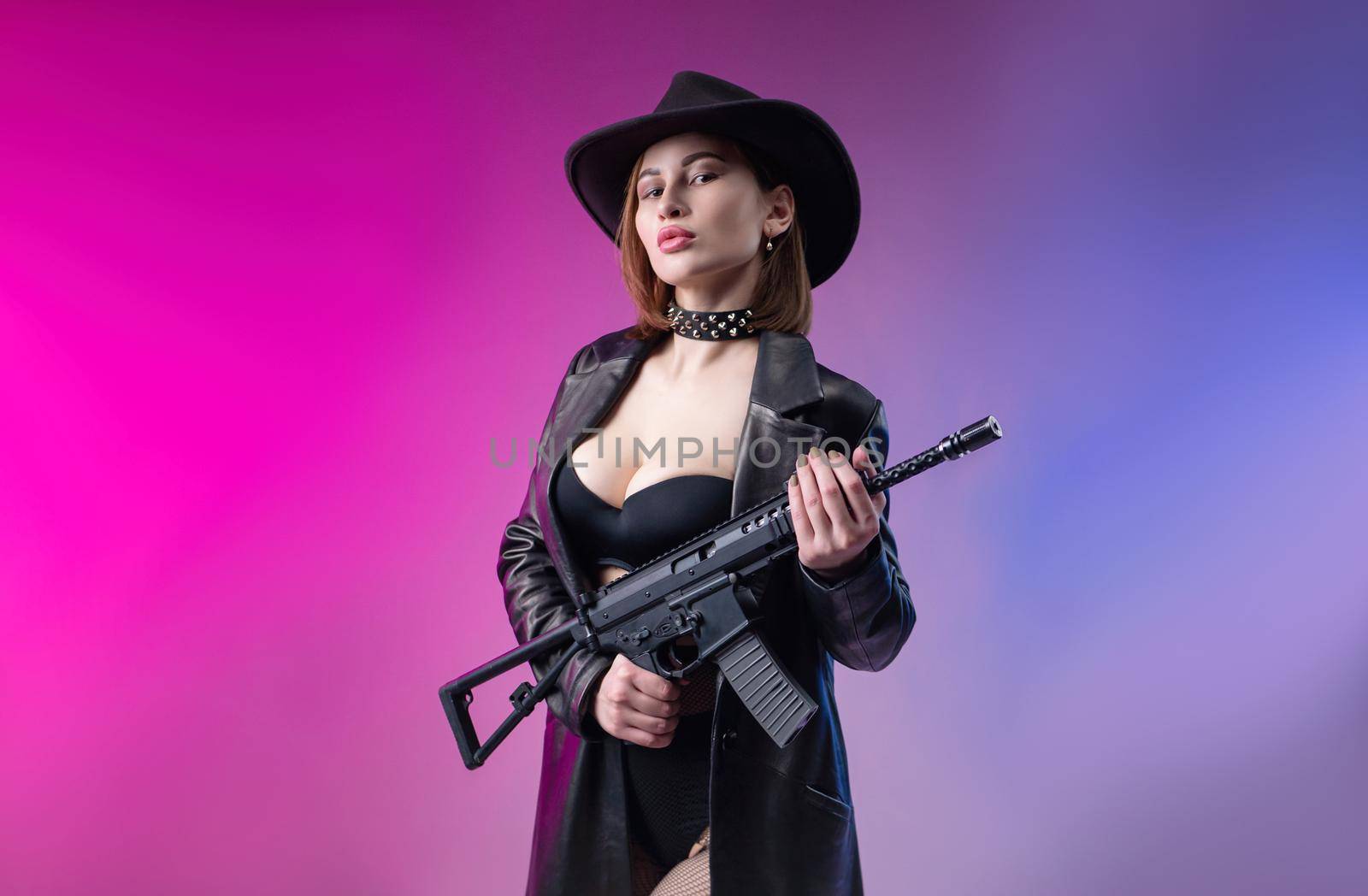 the sexy woman with an automatic rifle in black leather clothes and hat