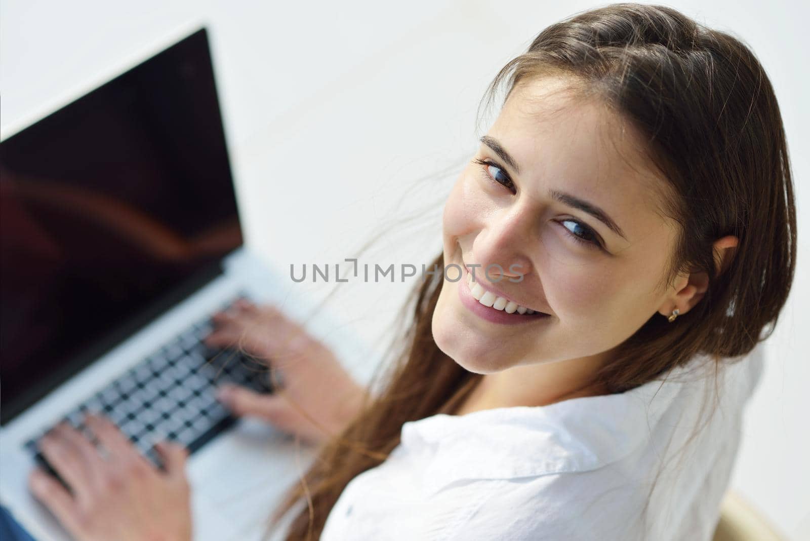 relaxed young woman at home working on laptop computer by dotshock