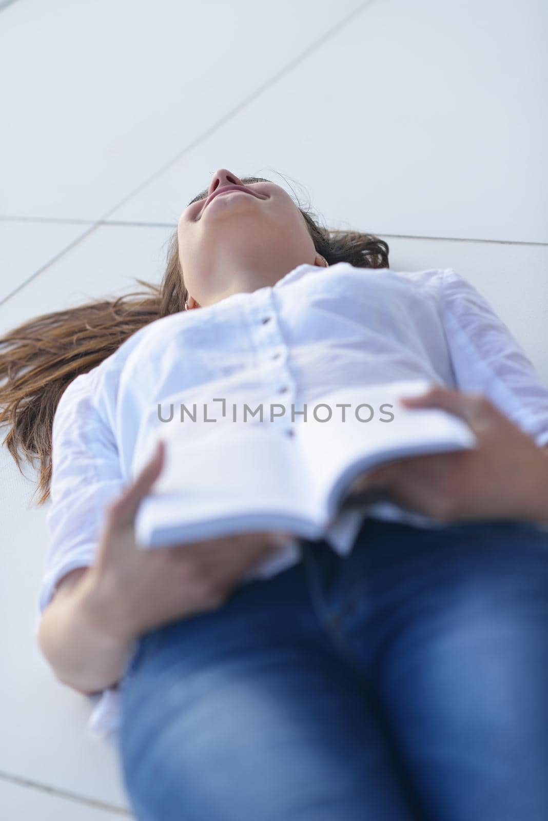 beautiful young woman relax and work on laptop computer while listening music on heaphones and read book at home