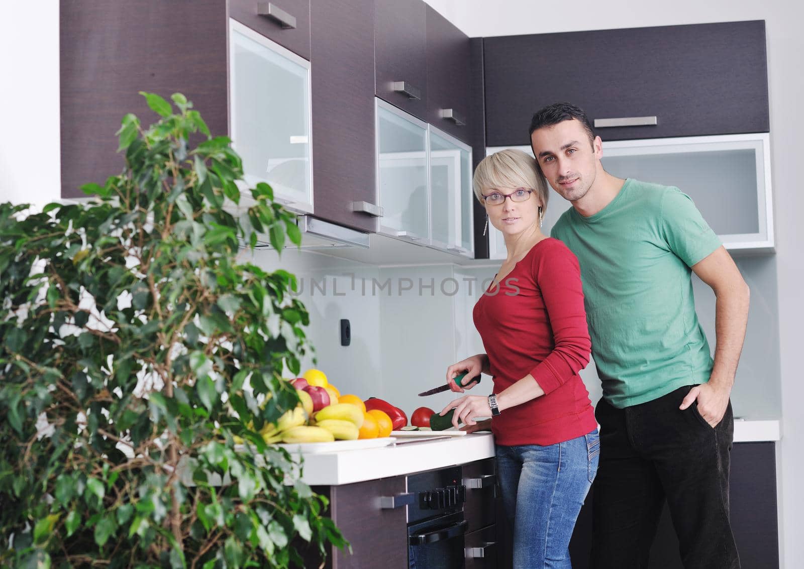 happy young couple have fun in  modern kitchen indoor  while preparing fresh fruits and vegetables food salad