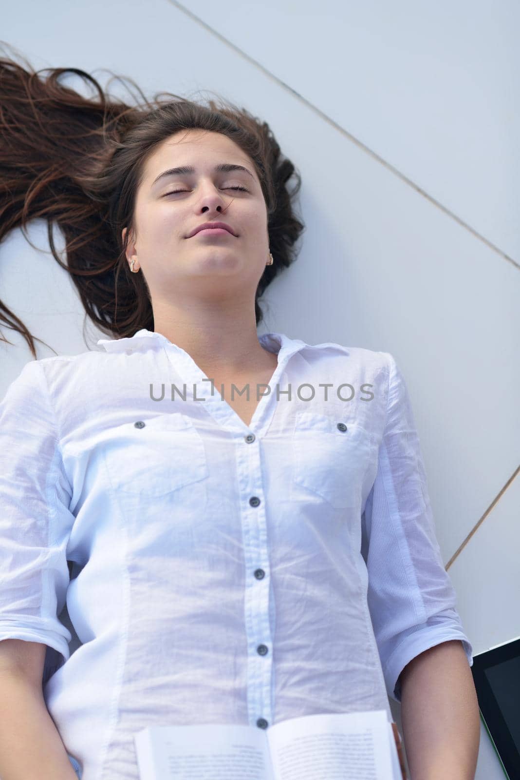 beautiful young woman relax and work on laptop computer while listening music on heaphones and read book at home