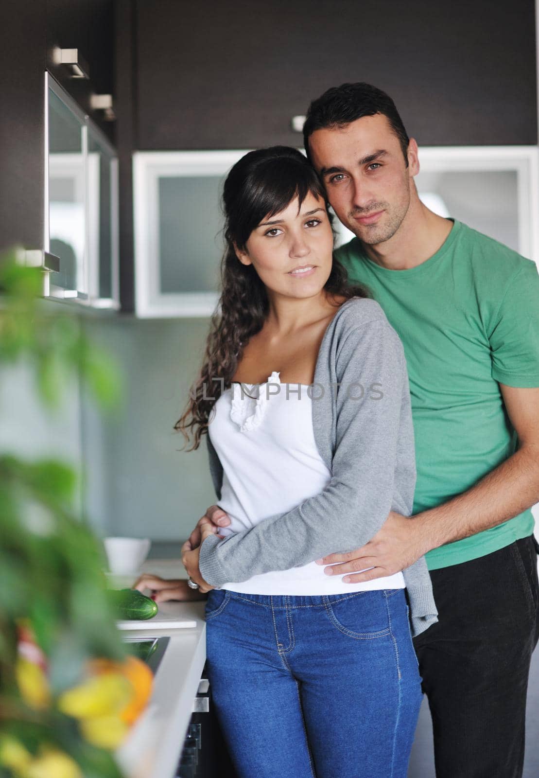 happy young couple have fun in  modern kitchen indoor  while preparing fresh fruits and vegetables food salad