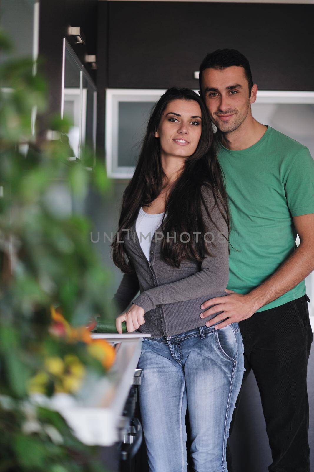 happy young couple have fun in  modern kitchen indoor  while preparing fresh fruits and vegetables food salad