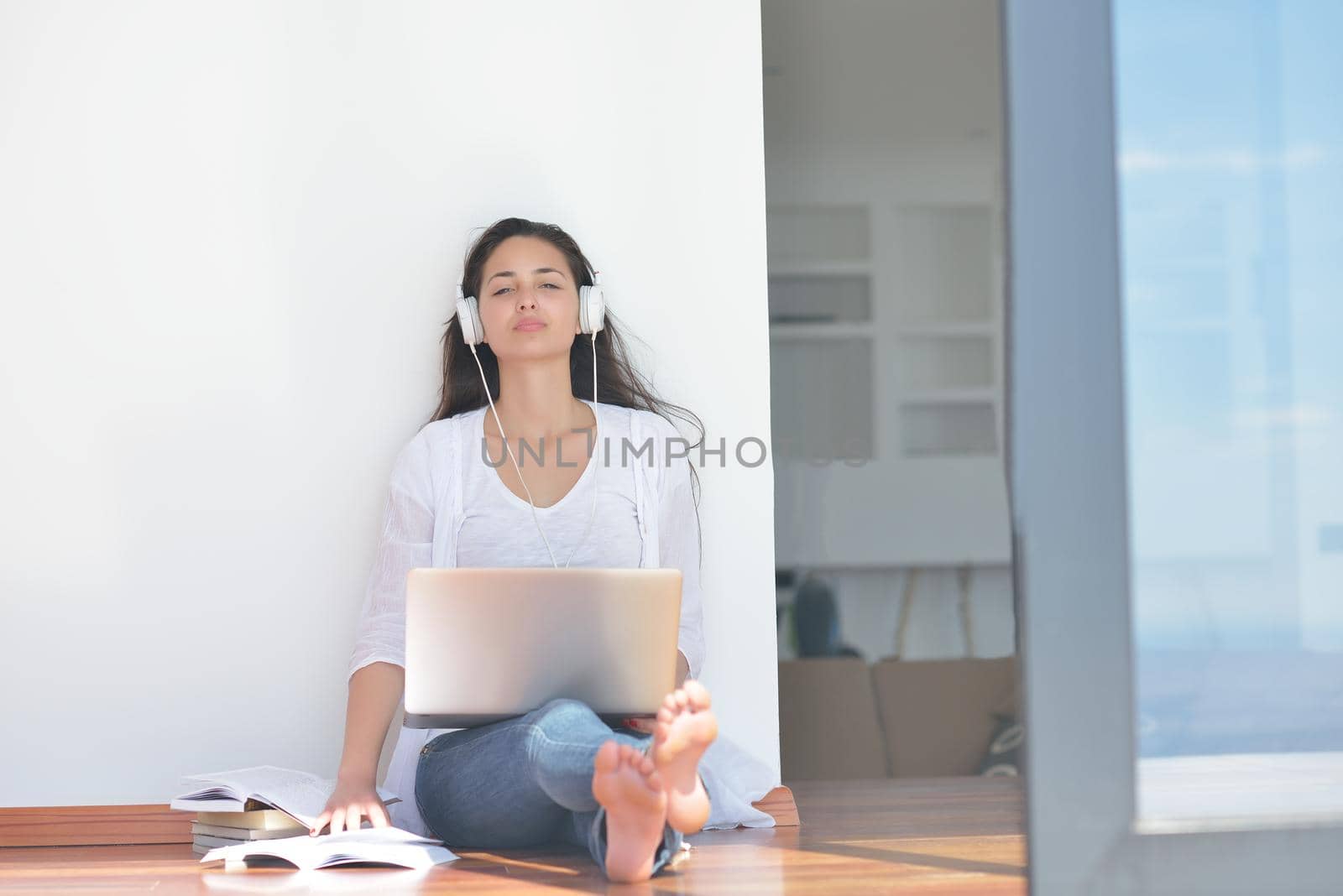 beautiful young woman relax and work on laptop computer while listening music on heaphones and read book at home