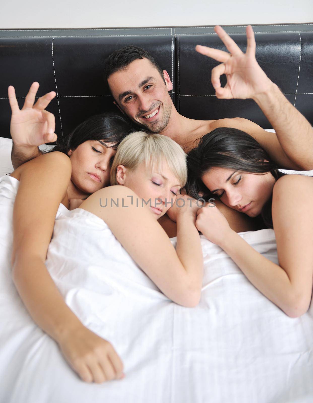 Young handsome man lying in bed with three girls by dotshock