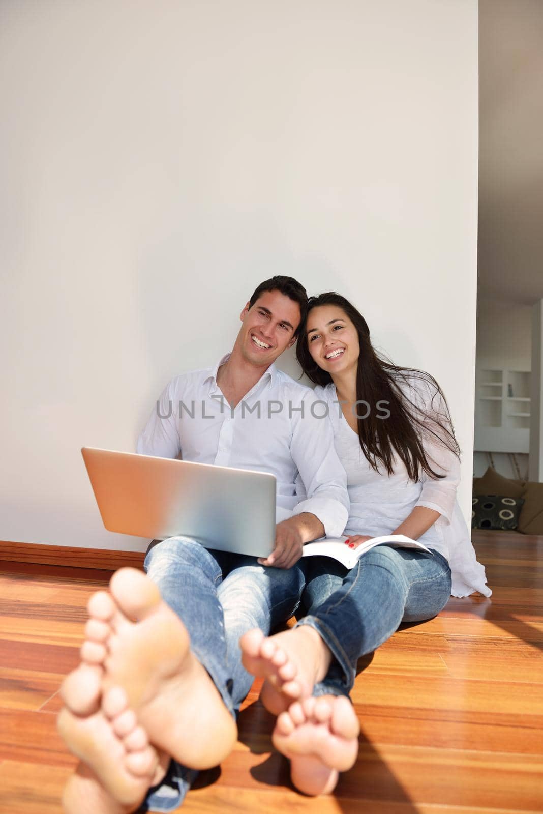 relaxed young couple working on laptop computer at home by dotshock