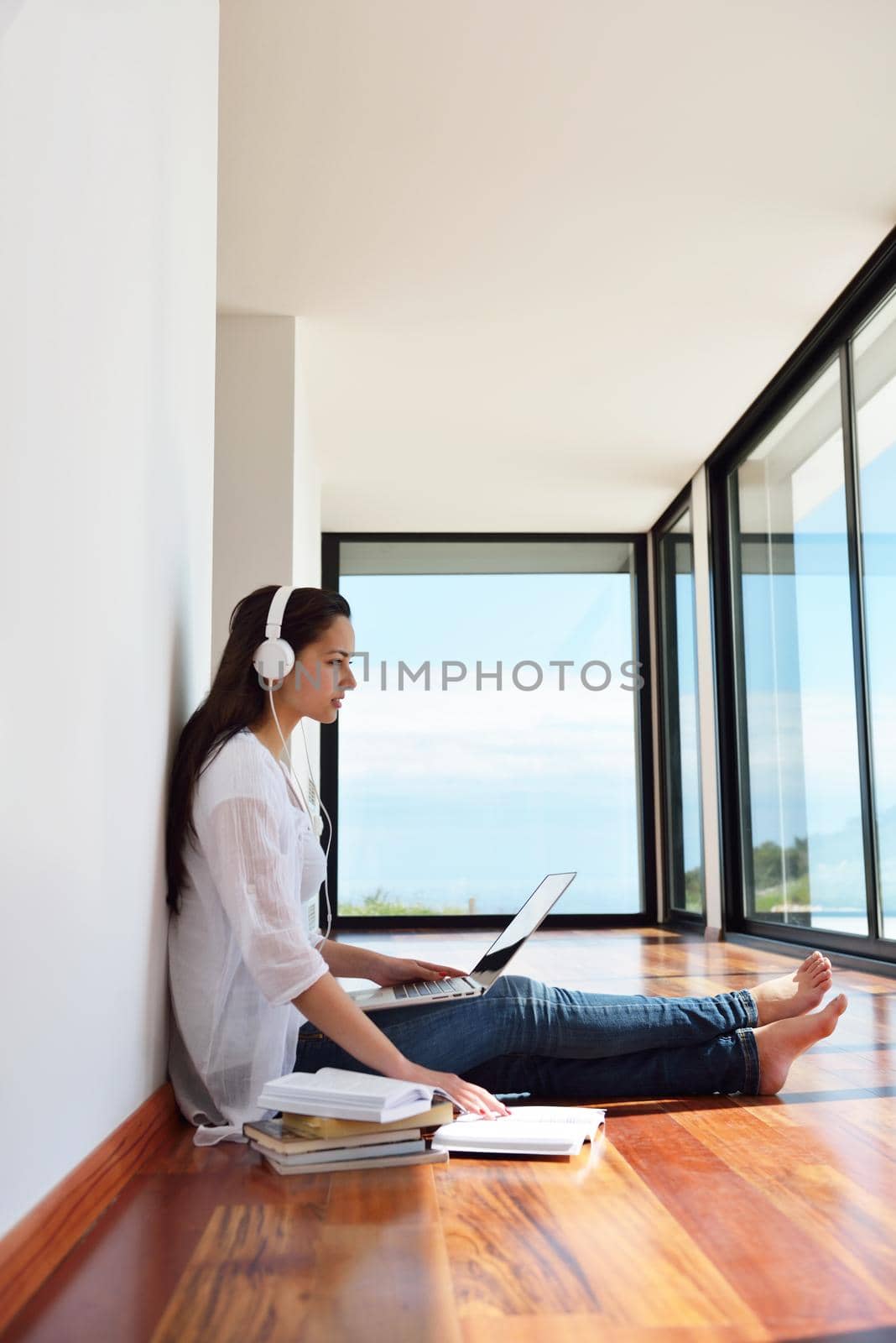 relaxed young woman at home working on laptop by dotshock