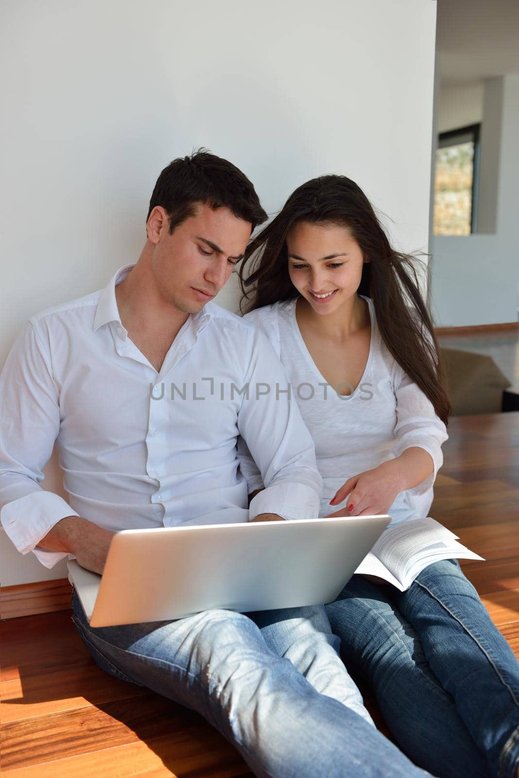 relaxed young couple working on laptop computer at home by dotshock