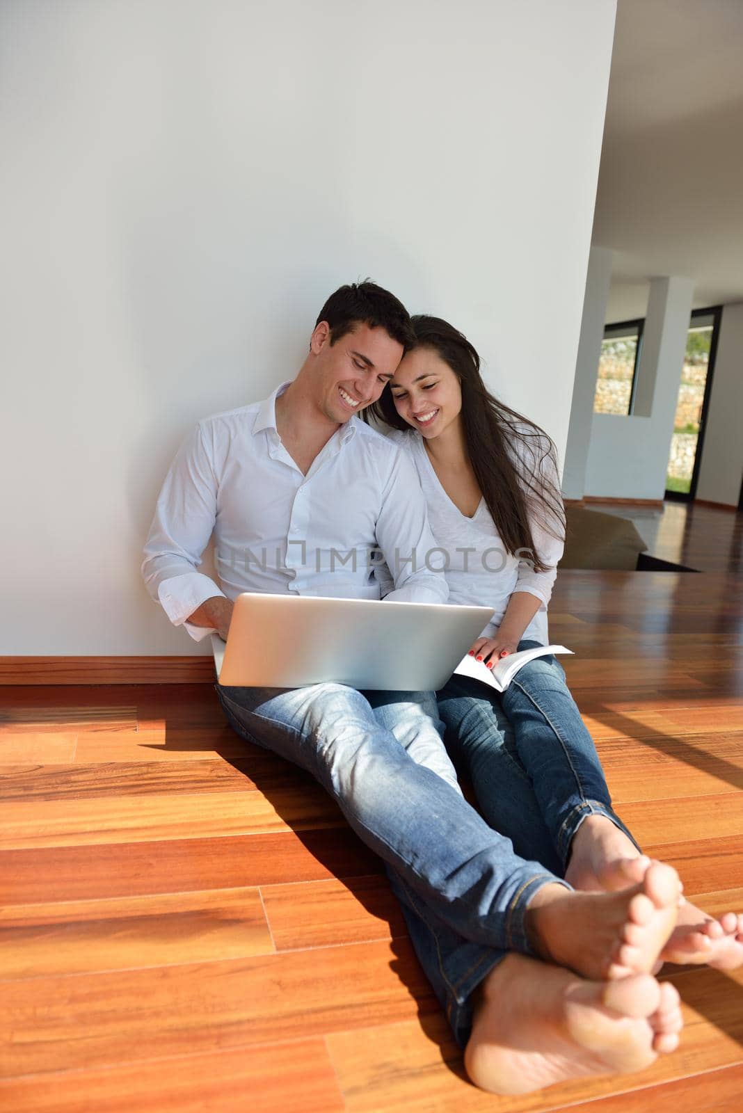 happy young relaxed  couple working on laptop computer at modern home indoor