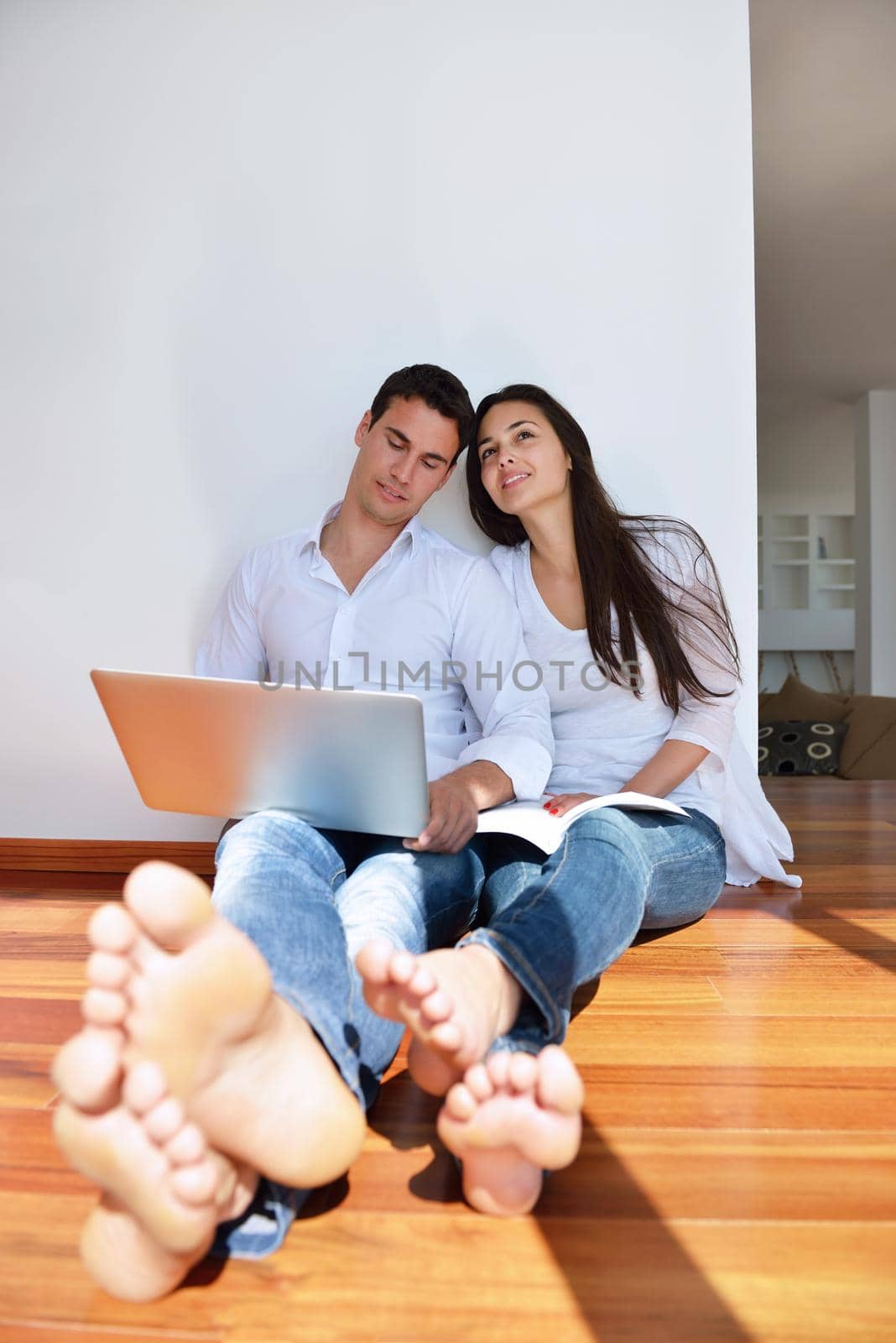 happy young relaxed  couple working on laptop computer at modern home indoor