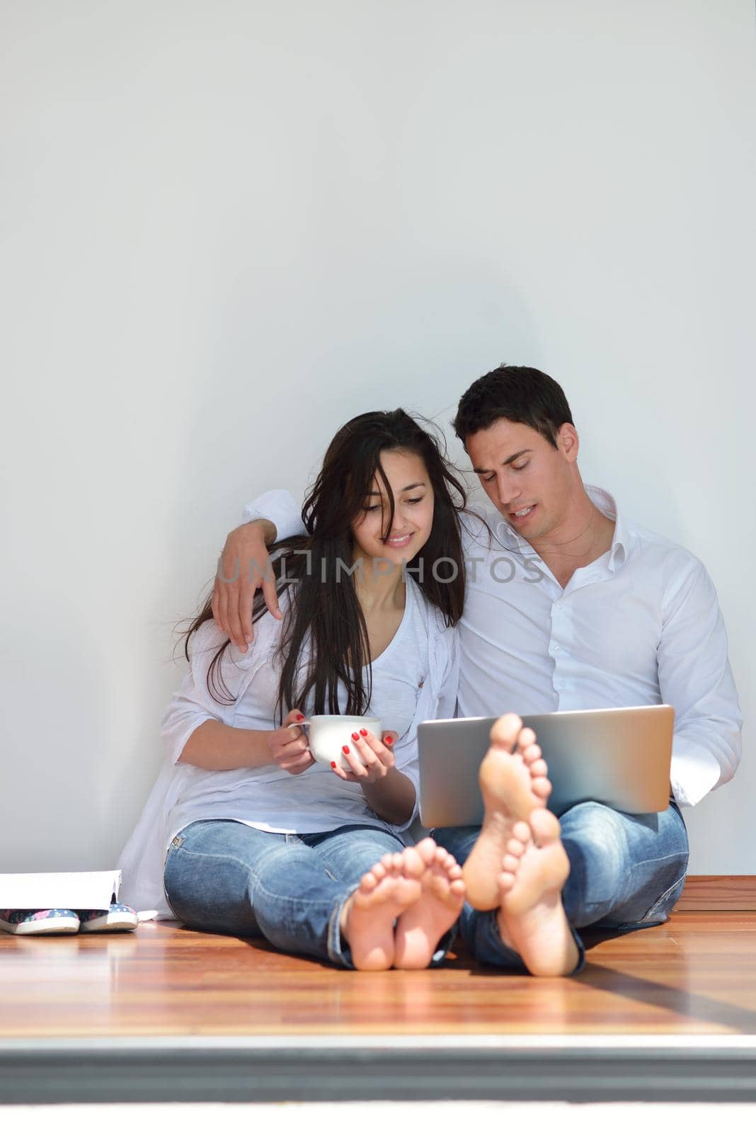 happy young relaxed  couple working on laptop computer at modern home indoor