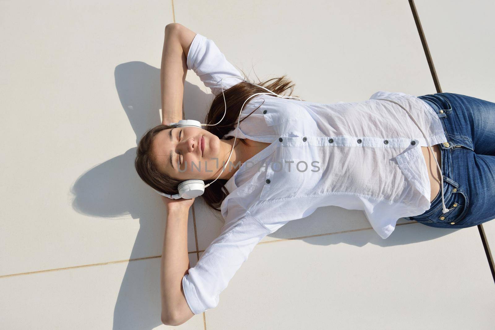 Young relaxed girl listening to the music on white headphones  in modern home interior