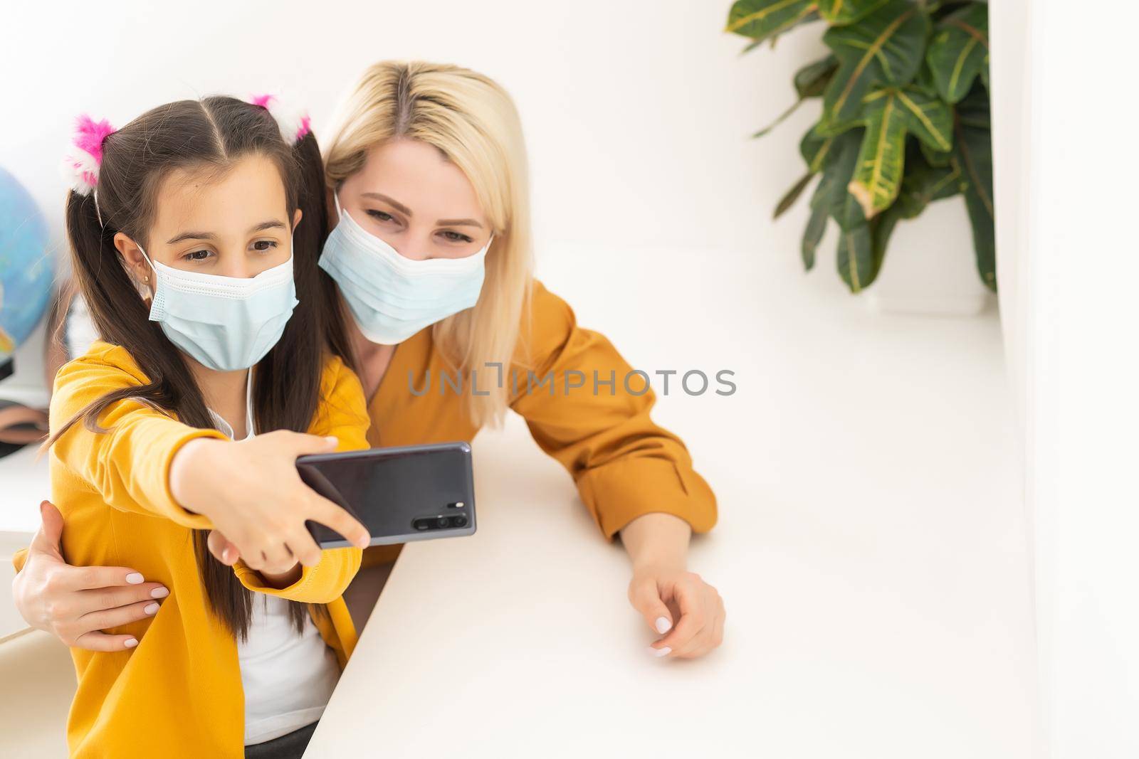 Little girl and her young mother taking a selfie wearing surgical mask