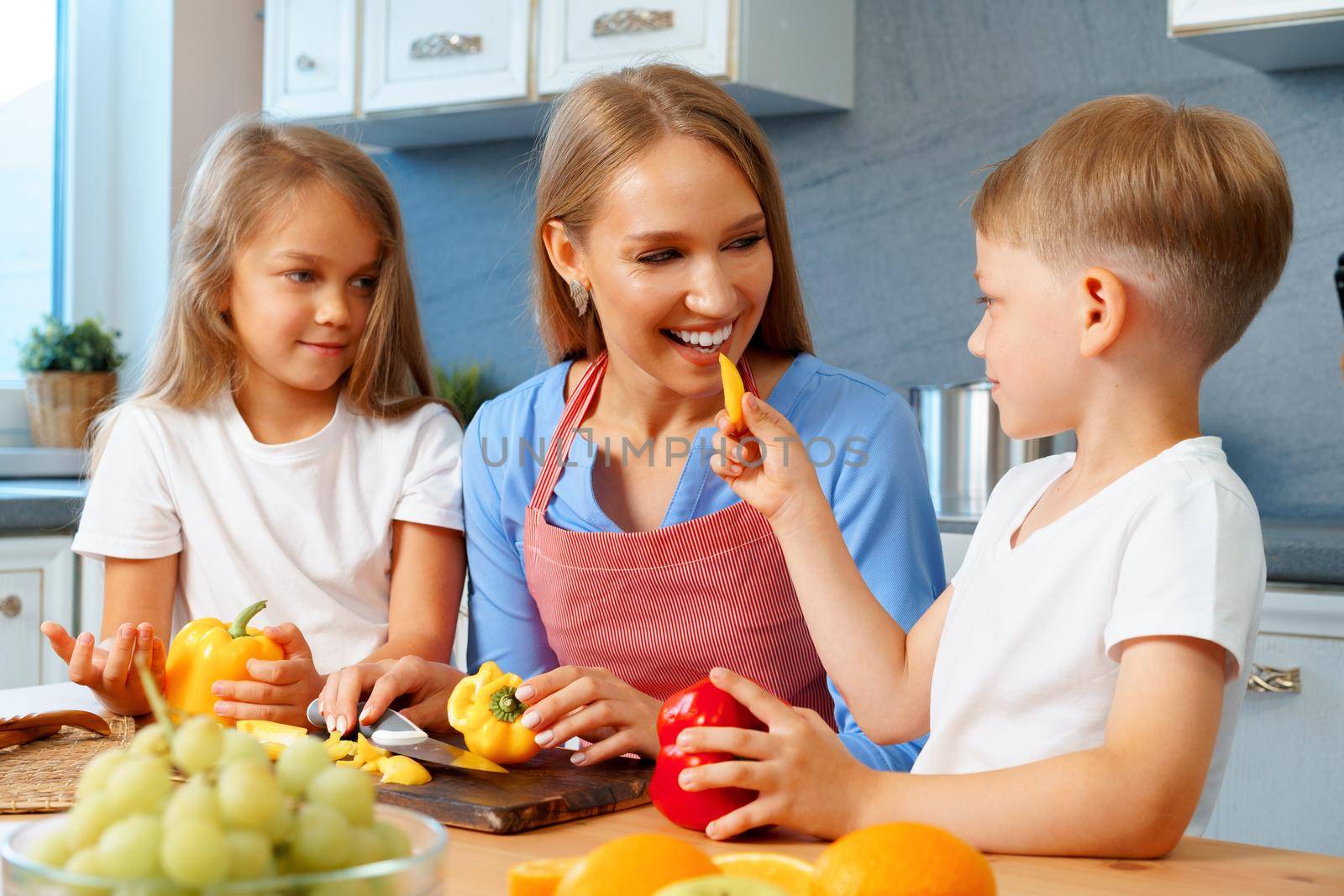 Mother cooking with her children in kitchen by Fabrikasimf