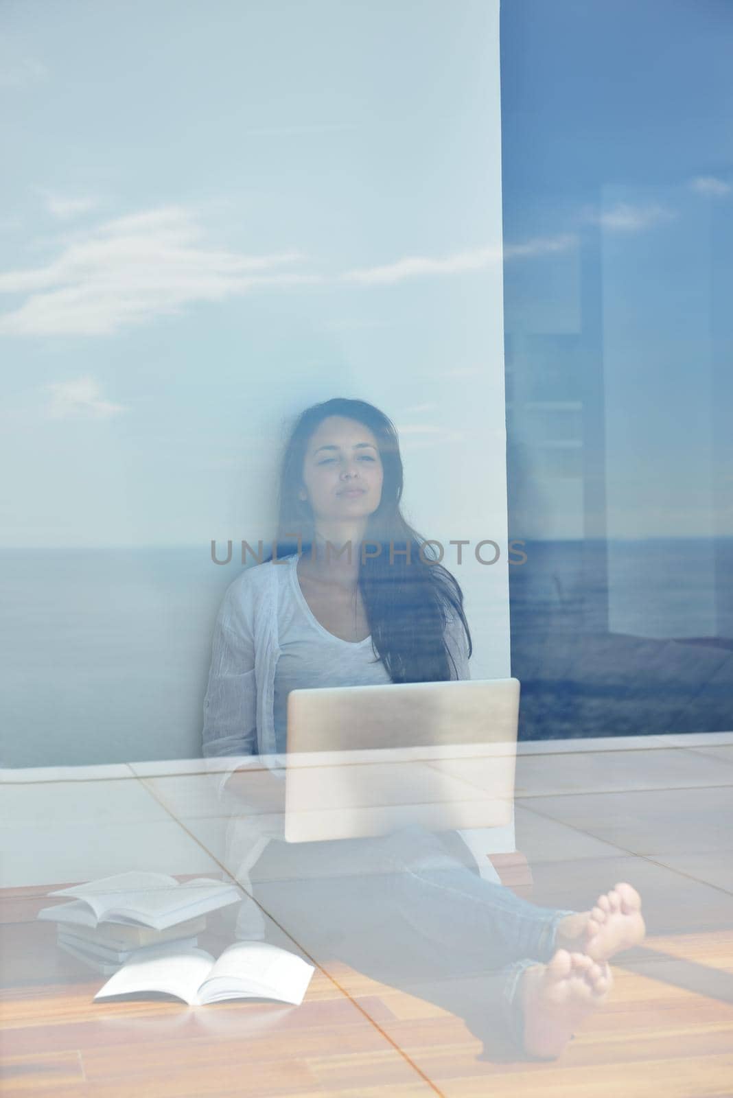 relaxed young woman at home working on laptop computer by dotshock