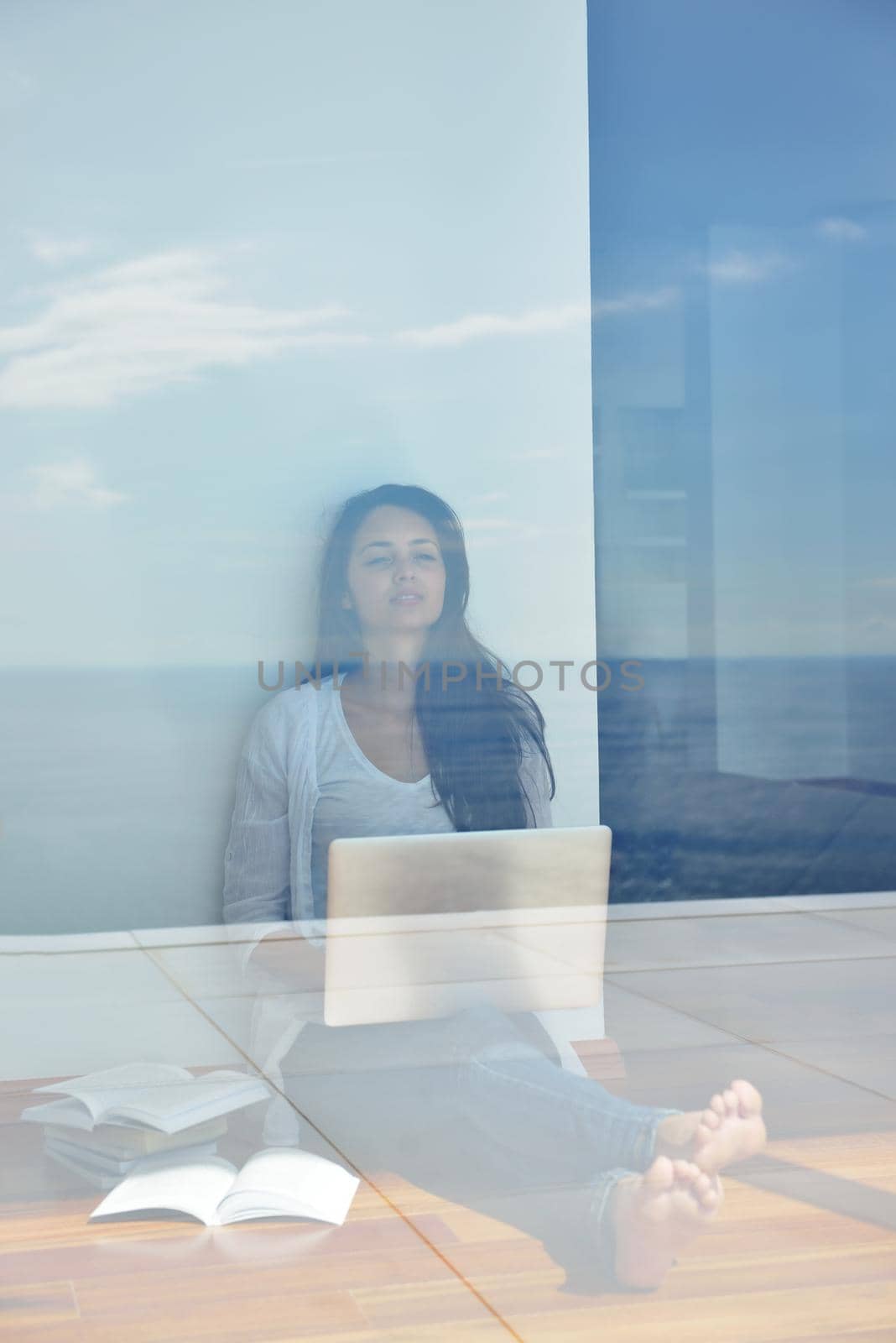 relaxed young woman at home working on laptop computer by dotshock