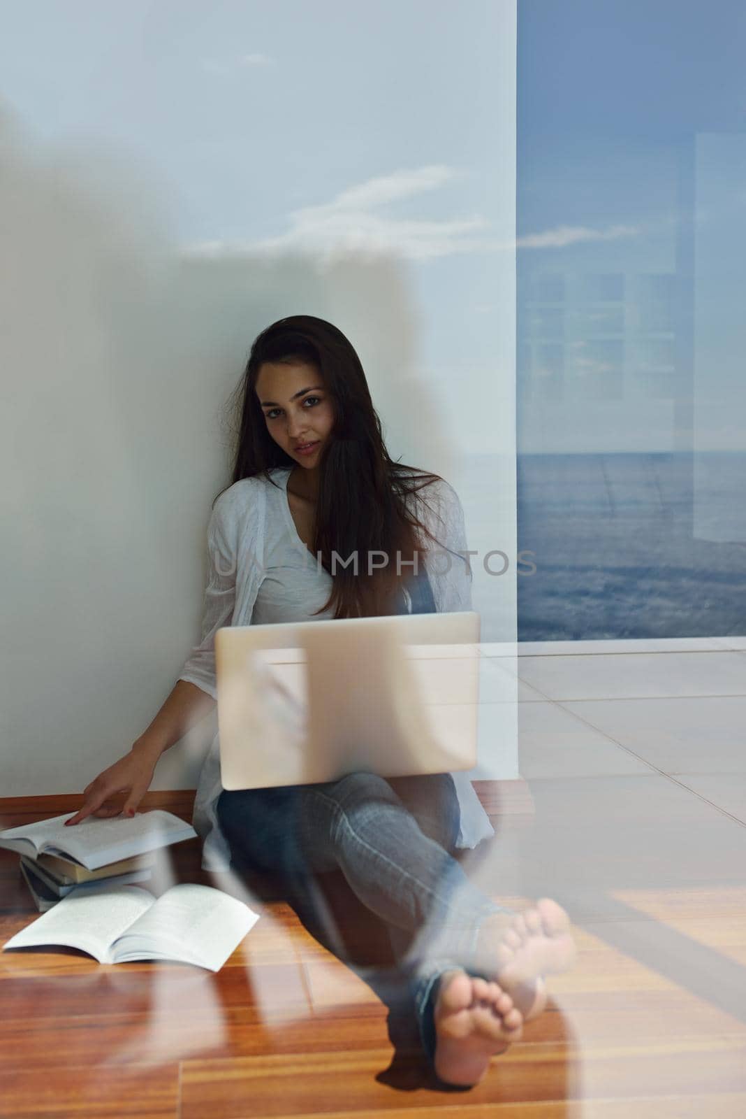 relaxed young woman at home working on laptop computer by dotshock