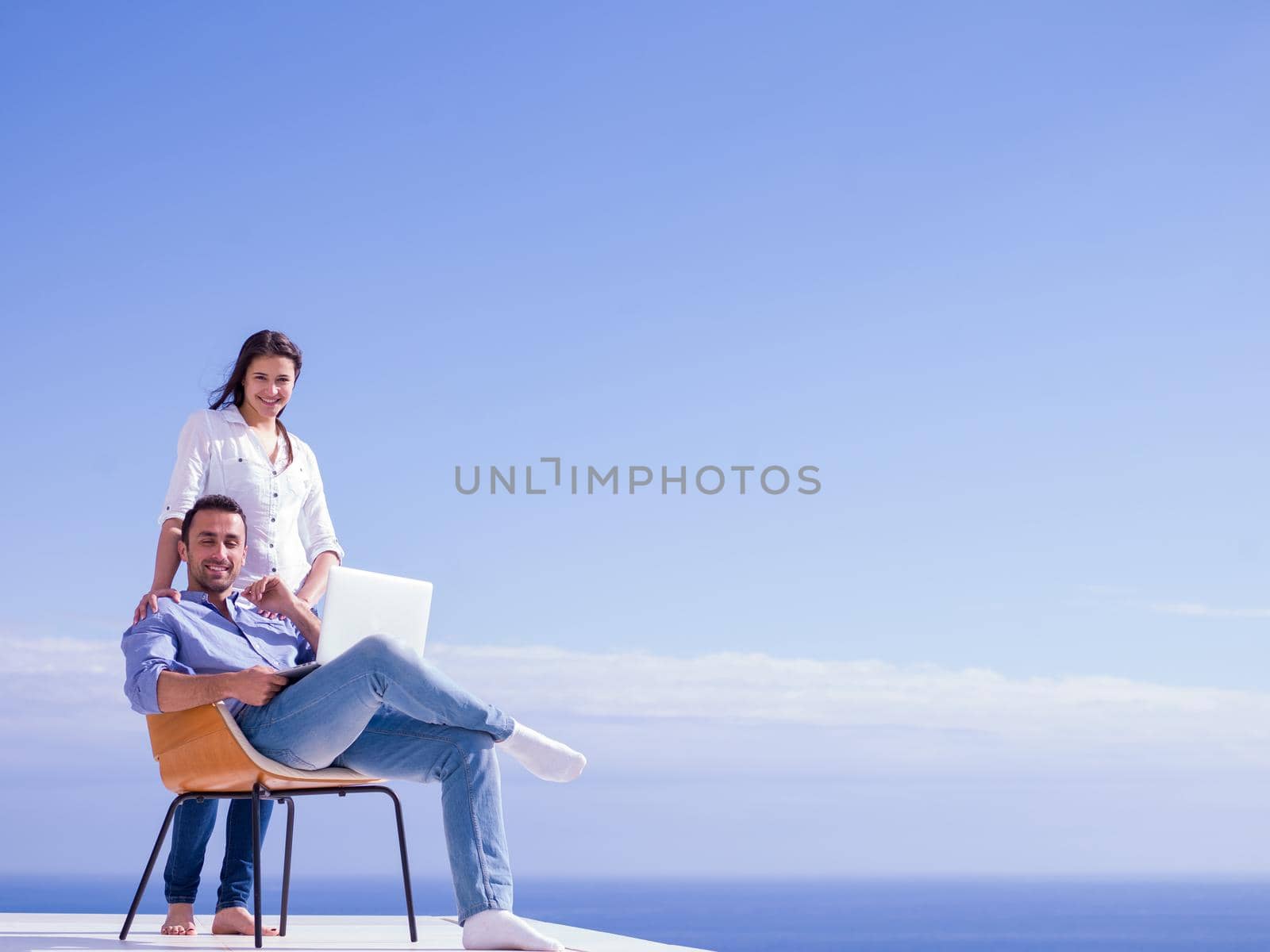 happy young relaxed  couple working on laptop computer at modern home indoor