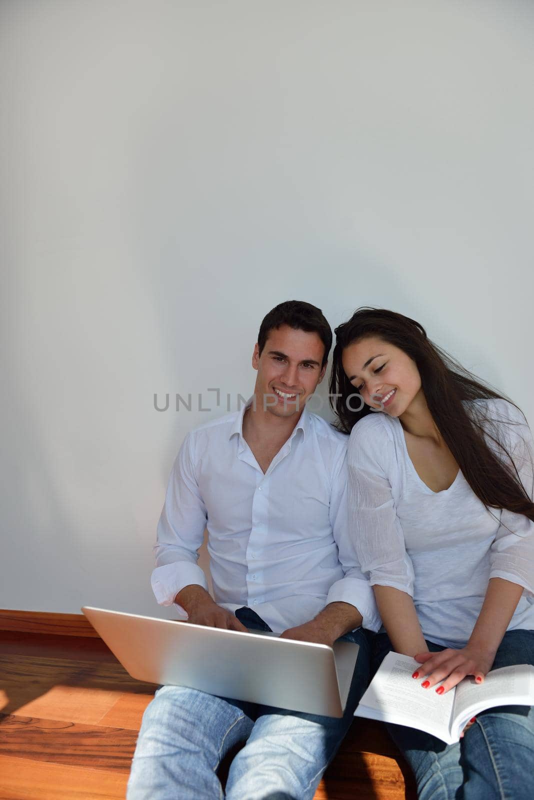 happy young relaxed  couple working on laptop computer at modern home indoor