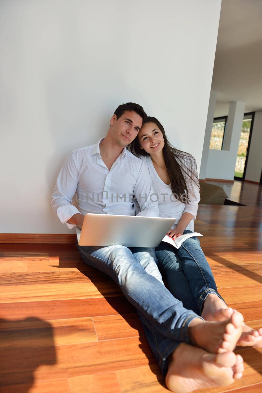 happy young relaxed  couple working on laptop computer at modern home indoor