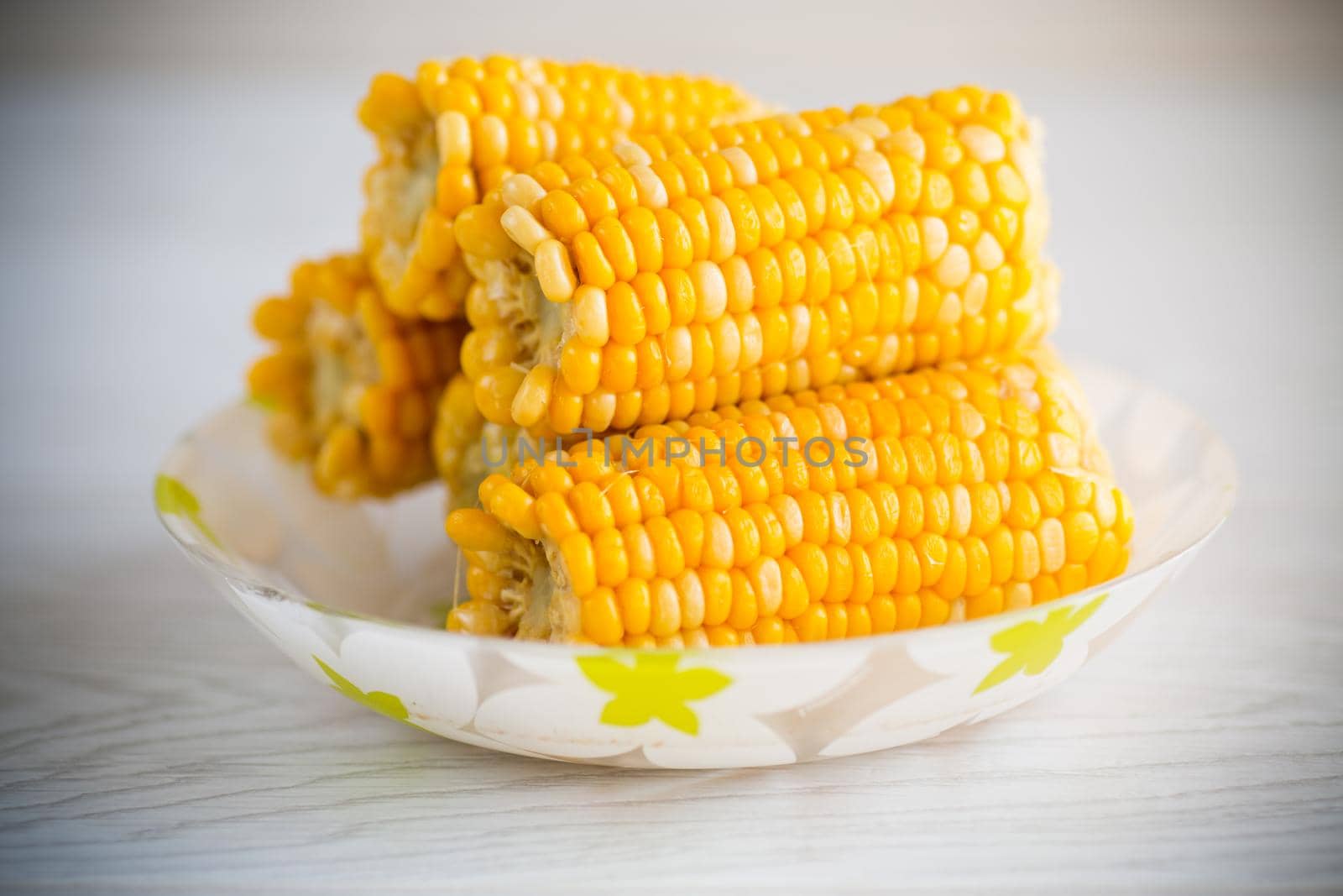 a few heads of boiled corn on a plate on the table