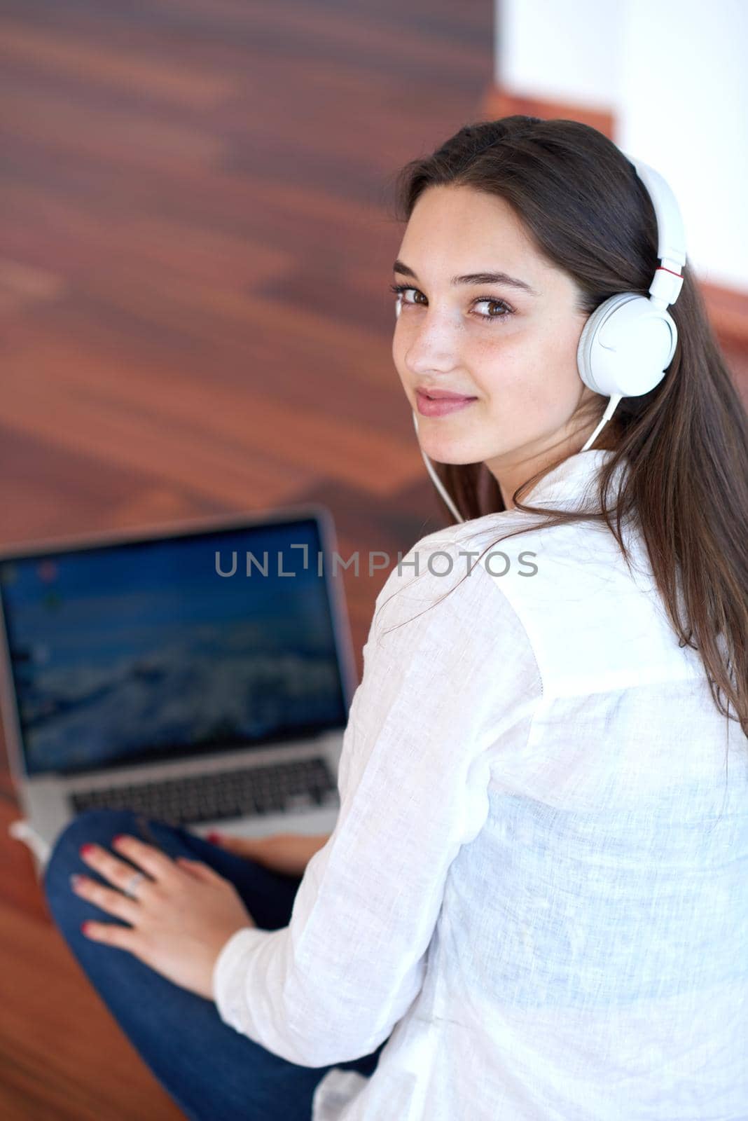 beautiful young woman relax and work on laptop computer modern  home office while listening musin on white headphones